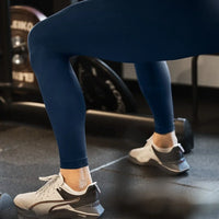 Träning i gym i marinblå kompressionstights och träningsskor