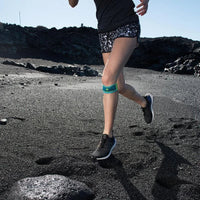 Löpare på en svart sandstrand med Sports Knee Strap under knät