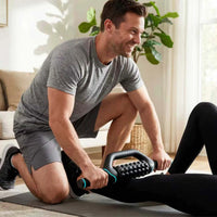 Man masserar baksidan av benet på en liggande person med Fitpaddy FitRoller