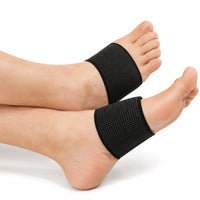 Svarta elastiska fotvalvsstöd med kroppsnära passform, burna runt mellanfoten på båda fötterna.