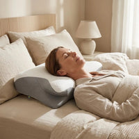 Skandinavisk kvinna som vilar i säng med ergonomisk sovkudde i mjukt quiltat material.